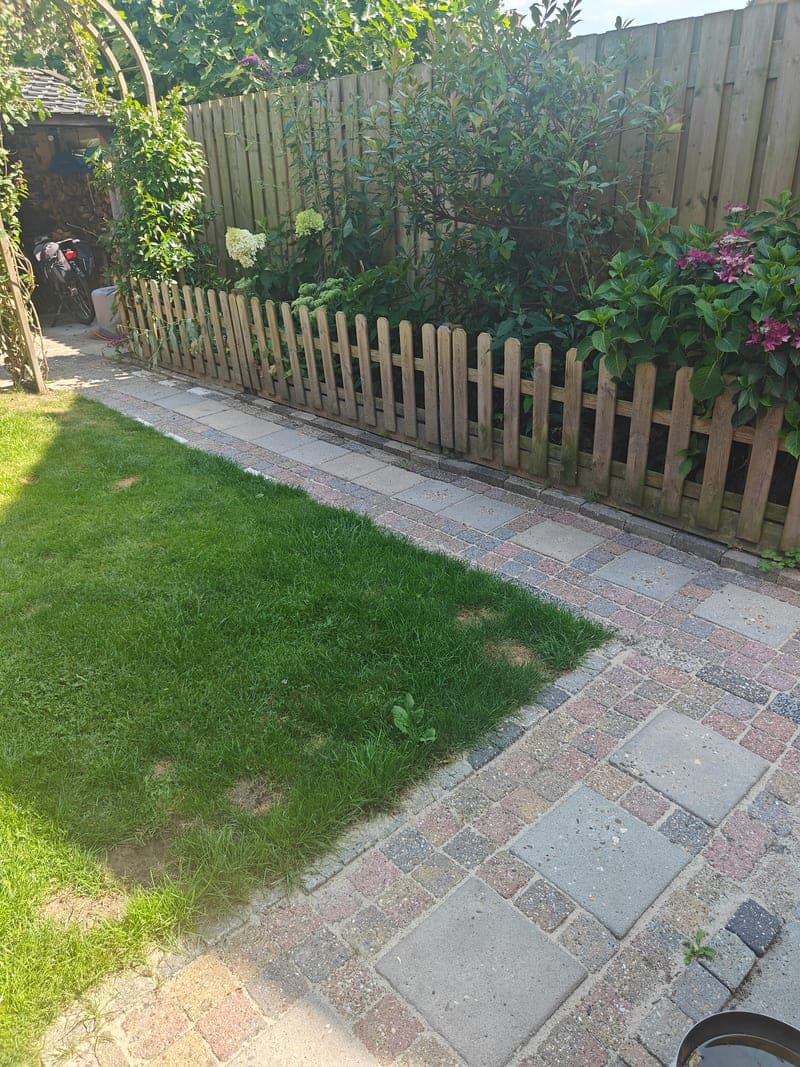 Gereinigd pad langs een gazon met een houten tuinhek