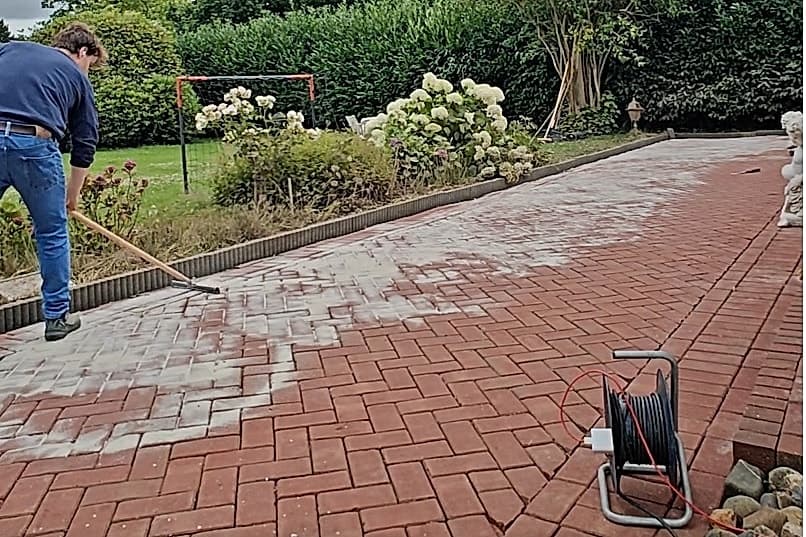 Henry veegt vers voegzand in de gereinigde bestrating