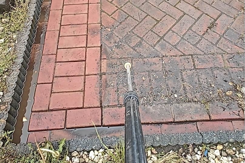 De hogedruklans in actie op een oprit van rode klinkers