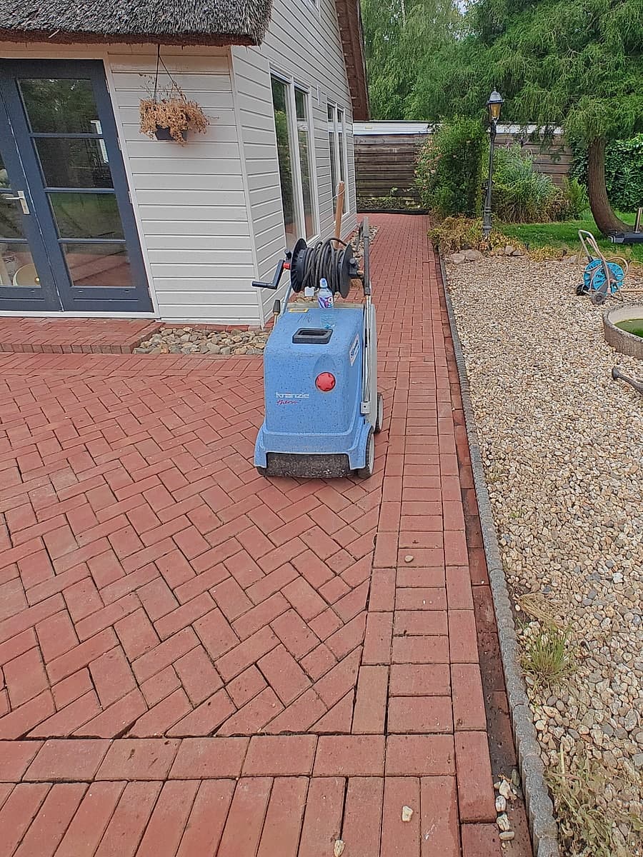 De hogedrukreiniger staat klaar op het terras tijdens de klus